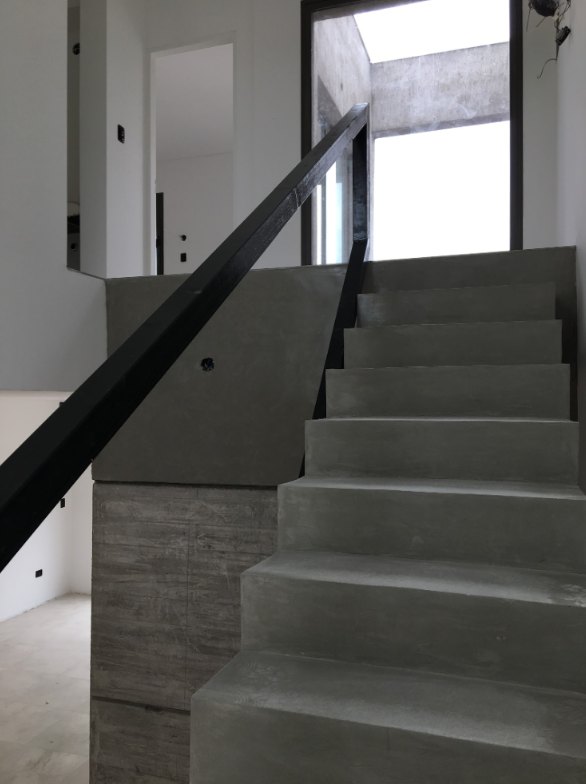 Escalera revestida en microcemento con baranda negra