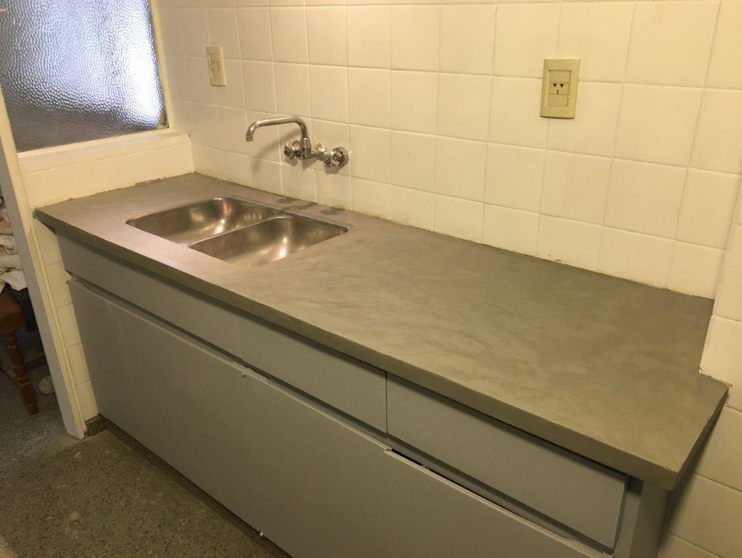 Mesada de cocina revestida en microcemento con bacha de acero