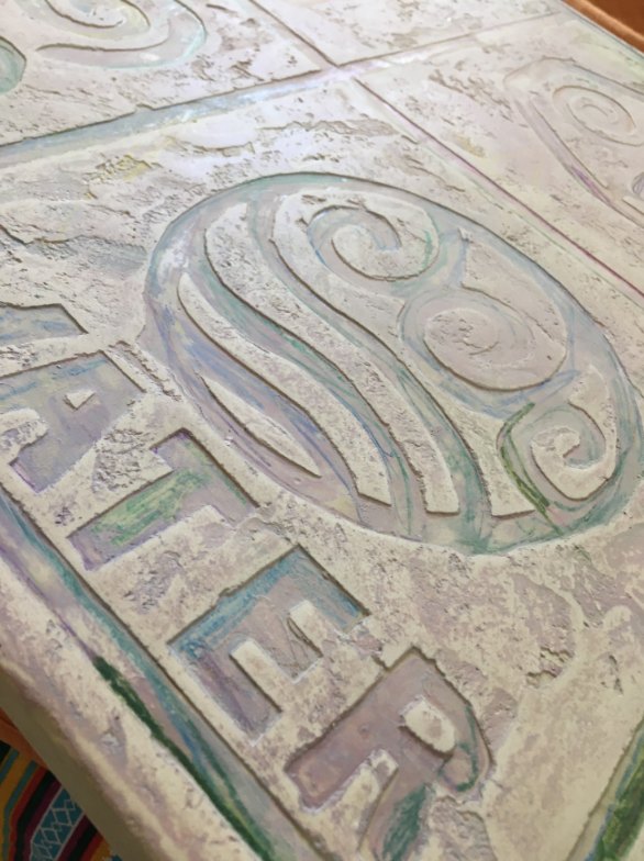Panel de microcemento con relieve de olas y la palabra water