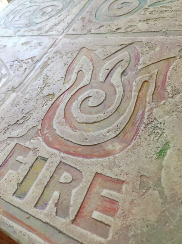 Panel de microcemento con relieve de llama y la palabra fire